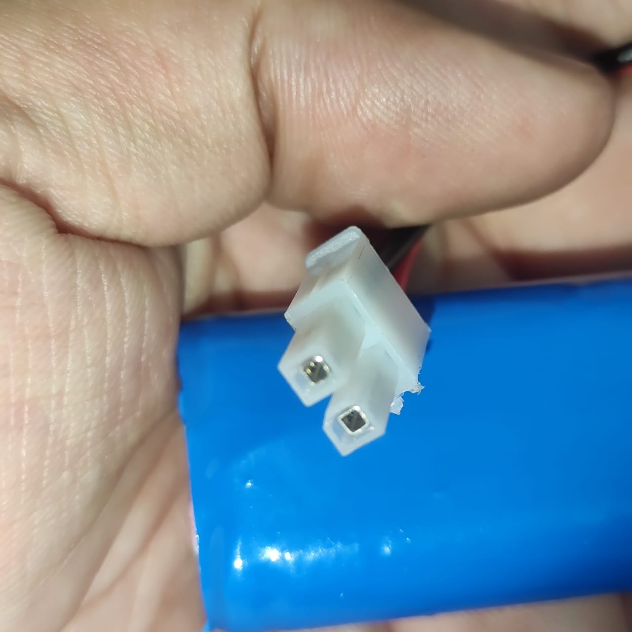 On Demand 7.4V Li Ion Battery For 3HAC044075 Replacement - a close-up view of the white two-pin plastic connector attached to the blue battery pack.