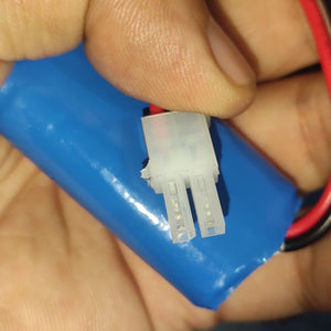 On Demand 7.4V Li Ion Battery For 3HAC044075 Replacement - close-up of the blue cylindrical battery pack with a white two-pin connector held in a hand.