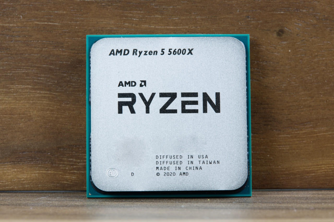 On Demand AMD Ryzen 5 5600X CPU - 6 Cores, 4.6 GHz Boost AM4 Socket - a square silver-topped processor with green edges, resting on a wooden surface.
