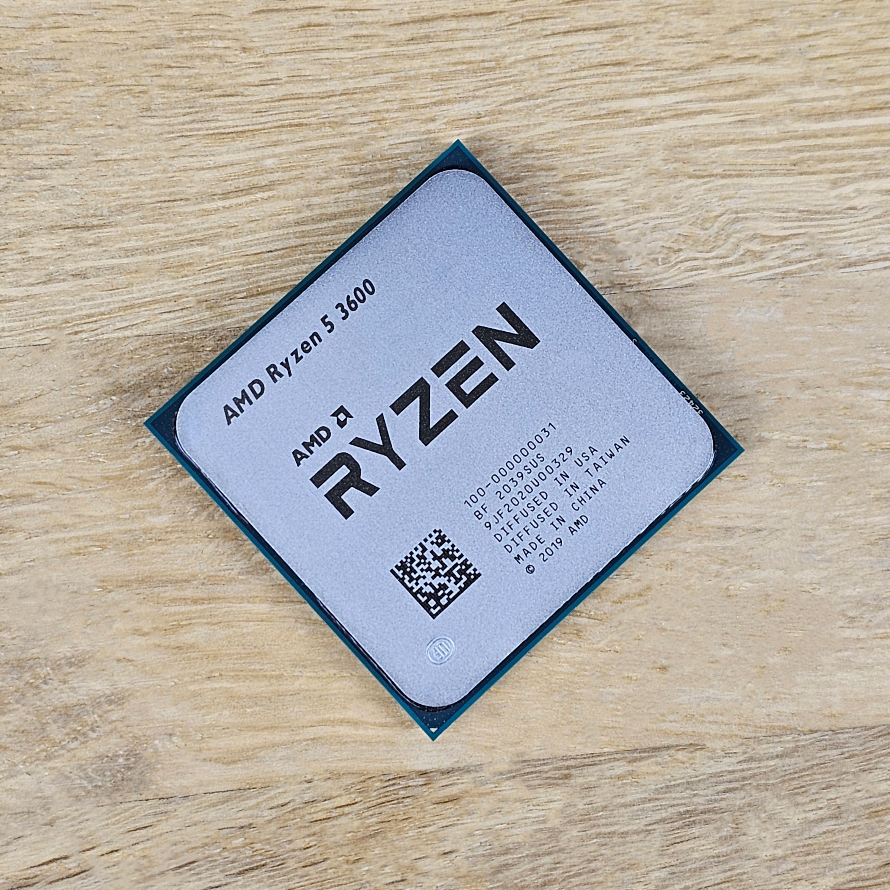 On-Demand AMD Ryzen R5 3600 Processor | 6-Core 12-Thread CPU for Gaming And Work - a square silver-topped CPU with black text and a QR code, resting on a light-colored wooden surface.