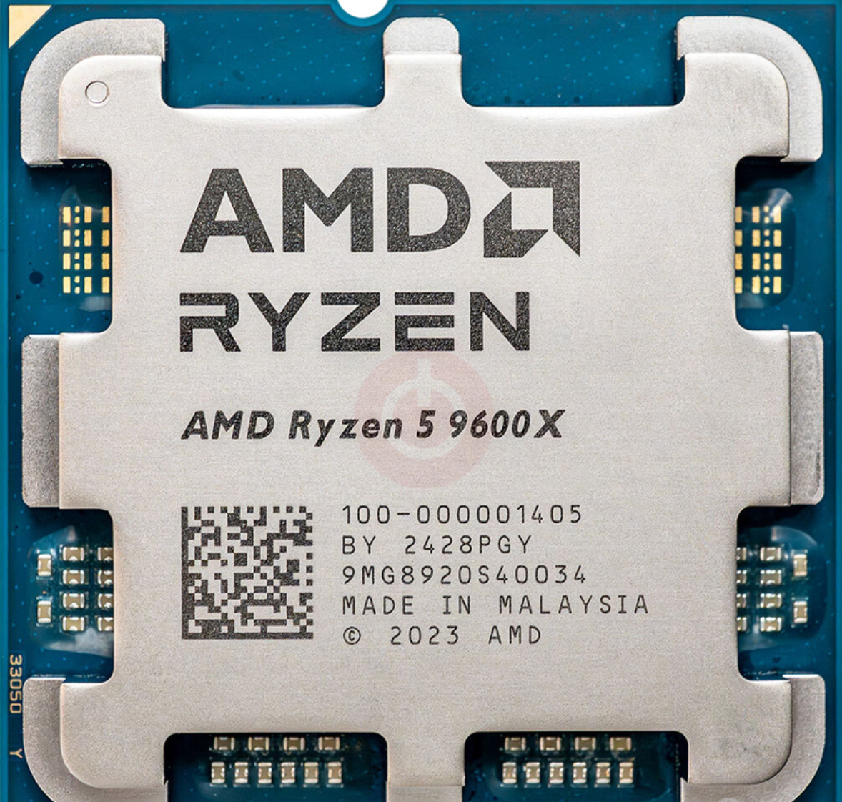 On Demand AMD Ryzen R5 9600X Processor 6 cores and 12 threads - a close-up top-down view of the silver metal integrated heat spreader on a blue square substrate with visible contact pads.