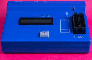 On Demand Cheapest Microcontroller - a blue device with a ZIF socket, a blank LCD screen, a Program button, and status LEDs on a pink background.