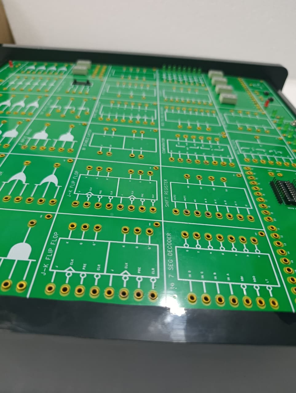 On Demand DLD Trainer Digital Logic Trainer WWW.DIGILOG.PK - a close-up of a green circuit board featuring labeled J-K flip-flop, shift register, and decoder sections.