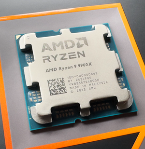 On Demand R9 9900X Processor 12-Core, 24-Thread - AMD Ryzen 9 9900X processor, a silver-coloured square CPU with an integrated heat spreader, resting on a flat surface with orange-bordered packaging.