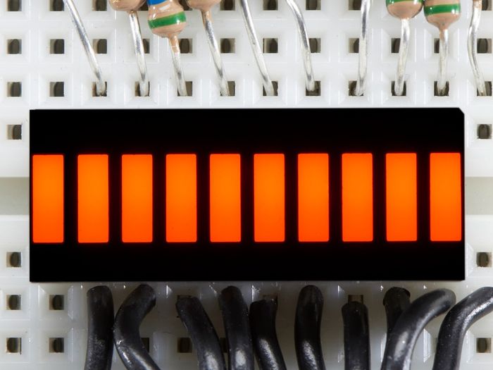 Orange 10 Segment Light Bar Graph LED Display - ten illuminated orange rectangular LED segments mounted on a breadboard with wires and resistors.