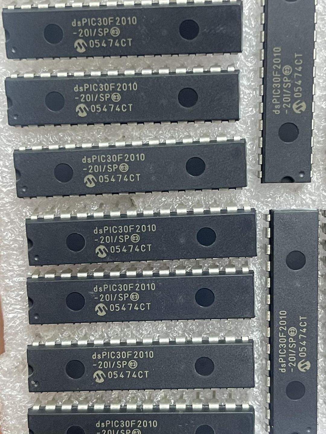Original Inverter IC DSPIC30F2010 Microcontroller Price - a collection of black 28-pin DIP integrated circuits arranged on protective bubble wrap.
