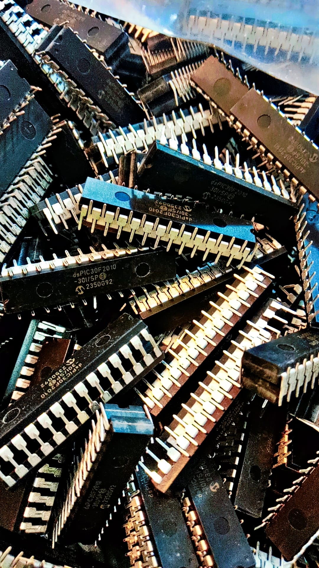 Original Inverter IC DSPIC30F2010 Microcontroller Price - a pile of black, rectangular dual-inline package integrated circuits with silver metal pins.