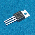 Original IRF3205 n Channel Power MOSFET - shown as a single black three-pin electronic component with a metal heat sink tab, resting on a textured blue surface.
