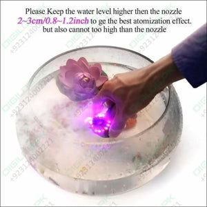 Original Ultrasonic Mist Maker Fogger 12 LED Colorful Light 24V 1A Humidifier with adapter - a hand holding the device submerged in a water bowl with a floating lotus flower.