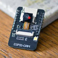 OV3660 ESP32-CAM WiFi + Bluetooth Camera Module Development Board ESP32 With Camera Module OV2640 For Arduino - a black rectangular development board with a central camera lens, a white ribbon cable connector, and an LED.