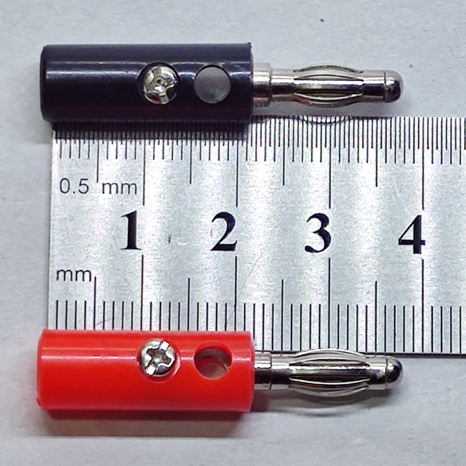 Pair of 4mm Banana Plugs - shown in black and red, positioned above a metal ruler to demonstrate their size.