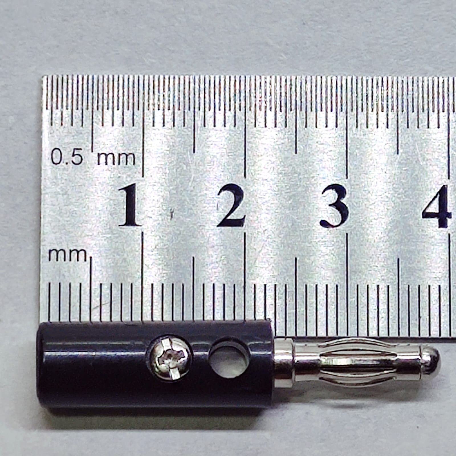 Pair of 4mm Banana Plugs - a black connector with a metal contact and screw terminal, shown in a close-up against a metal ruler for scale.