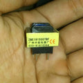 PCB Mount Current Transformer Current Sensor - a small yellow rectangular electronic component with two metal pins held in a hand.