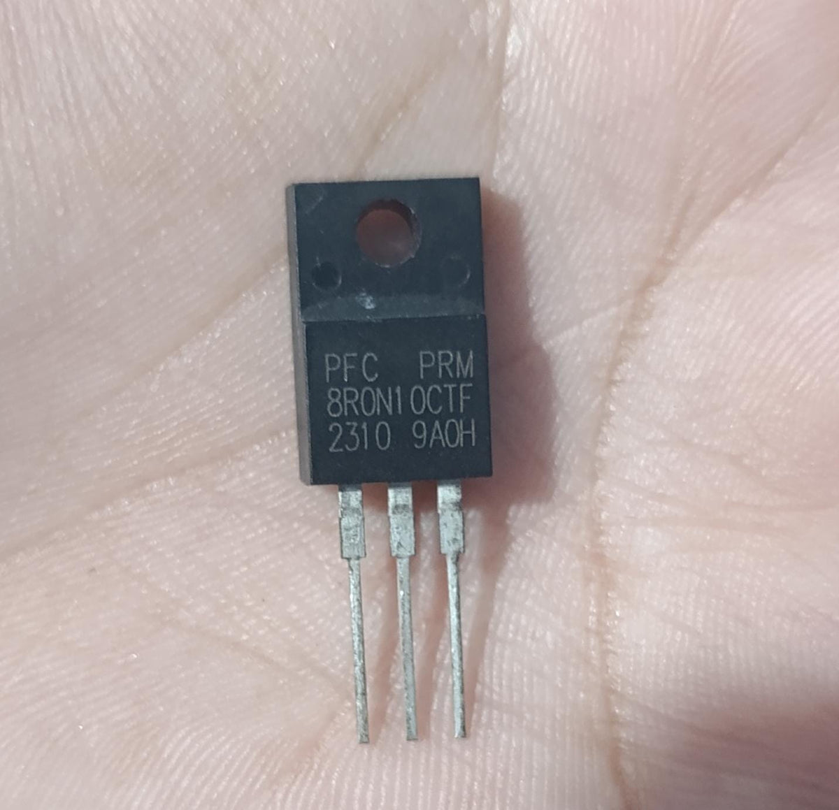 PFC PRM8R0N10CTF 100V N-Channel Power MOSFET (TO-220F) - a black TO-220F electronic component with three metal pins, held against a palm, showing the model text printed on the front.