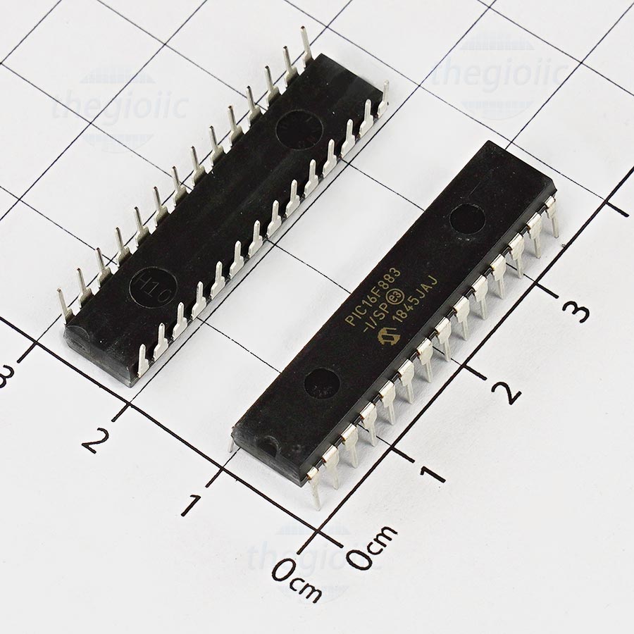 PIC16F883 IC Microcontroller PRICE - two black 28-pin dual in-line package integrated circuits placed on a white grid surface for scale.