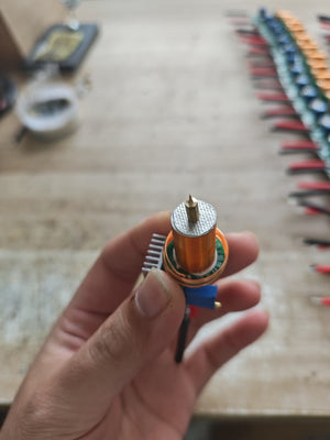 Plasma Arc Fire Head High-Frequency Electric Flame 15–24V Plasma Ignition Module-digilog.pk - a close-up showing the brass tip, copper coil, and silver heat sink held in a hand.