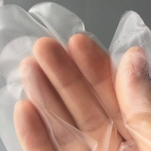 Plastic Surgical Disposable Hand Gloves - shown in a close-up view, featuring a clear, textured, thin plastic material worn over a human hand.