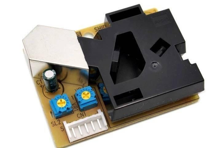 PM2.5 Dust Sensor DSM501 Dust Sensor Module - a black plastic housing, a metal shield, a white 5-pin connector, two blue potentiometers, and a capacitor.