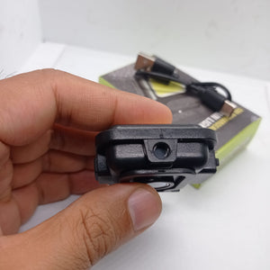 Portable COB Flashlight - Emergency Light with Rechargeable Keychain - Durable Plastic Casing - close-up of a black plastic casing held in a hand, showing a circular lens and a USB charging cable with its box in the background.