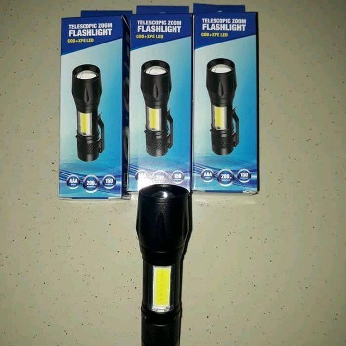 Portable Mini Telescopic Zoom Xpe COB LED Main Light White Light - one black flashlight placed in front of three identical retail boxes on a speckled surface.