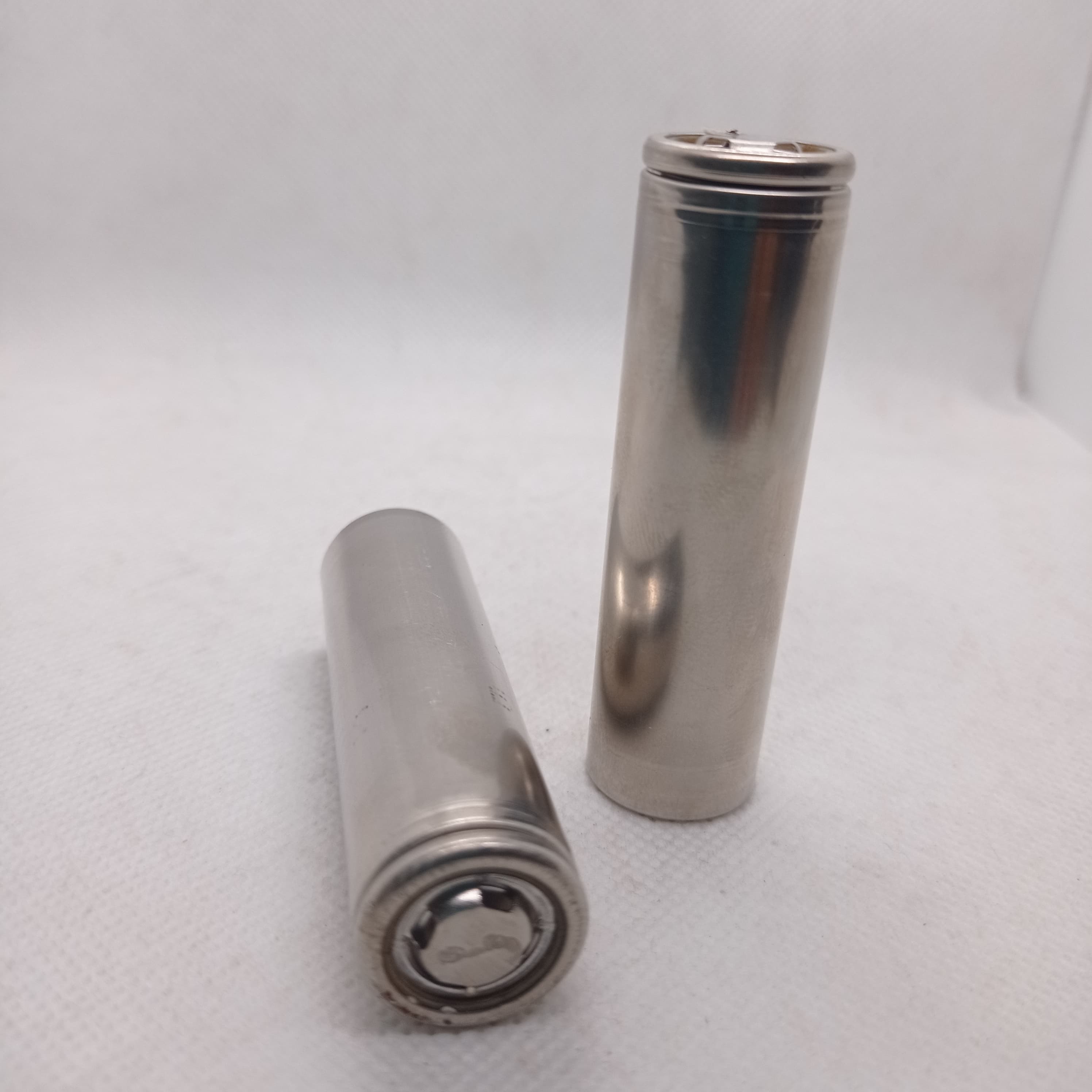 Pull-out Sony Murata Original Japanese 18650 Lithium Ion Cell 3.7V 2600mA Li Ion Battery Cell - two bare, silver-coloured cylindrical battery cells standing upright and lying on a white surface.