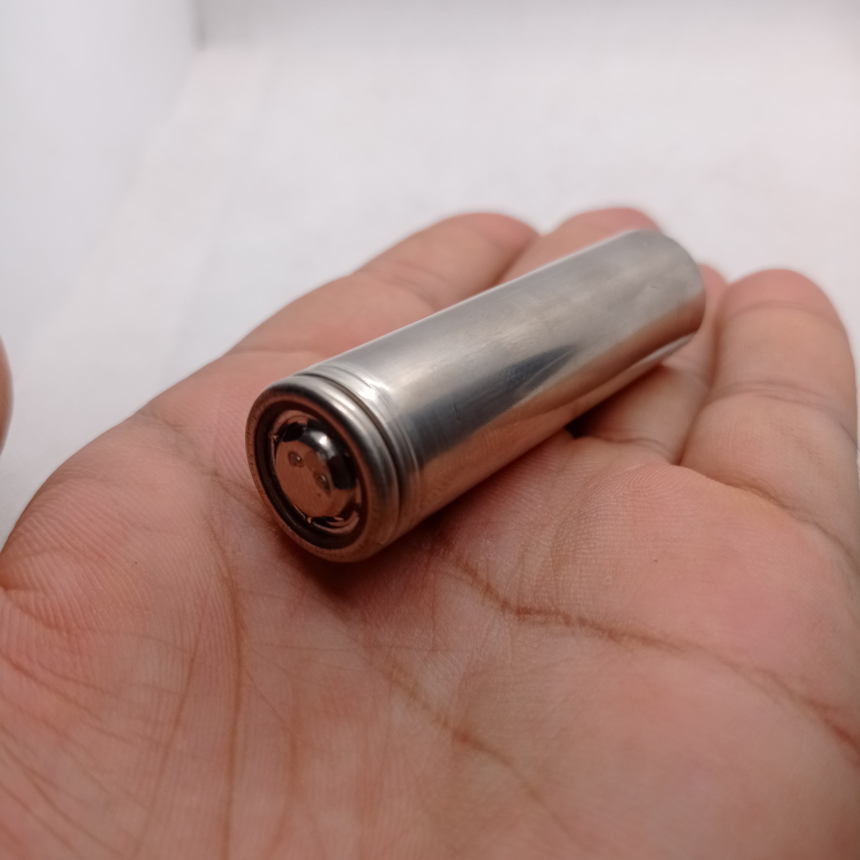 Pull-out Sony Murata Original Japanese 18650 Lithium Ion Cell 3.7V 2600mA Li Ion Battery Cell - a silver cylindrical metal battery held in a person's palm, showing the positive terminal end.