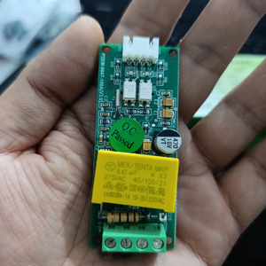 PZEM-004T 100A Single Phase Power Energy Meter Module - held in a hand, showing a green circuit board with a yellow capacitor, a four-pin terminal block, and a white connector port.