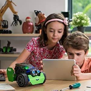 Q-scout STEM Robot For Kids By Robobloq - a green and black robot with glowing blue eyes, sits on a table while two children use a tablet nearby.