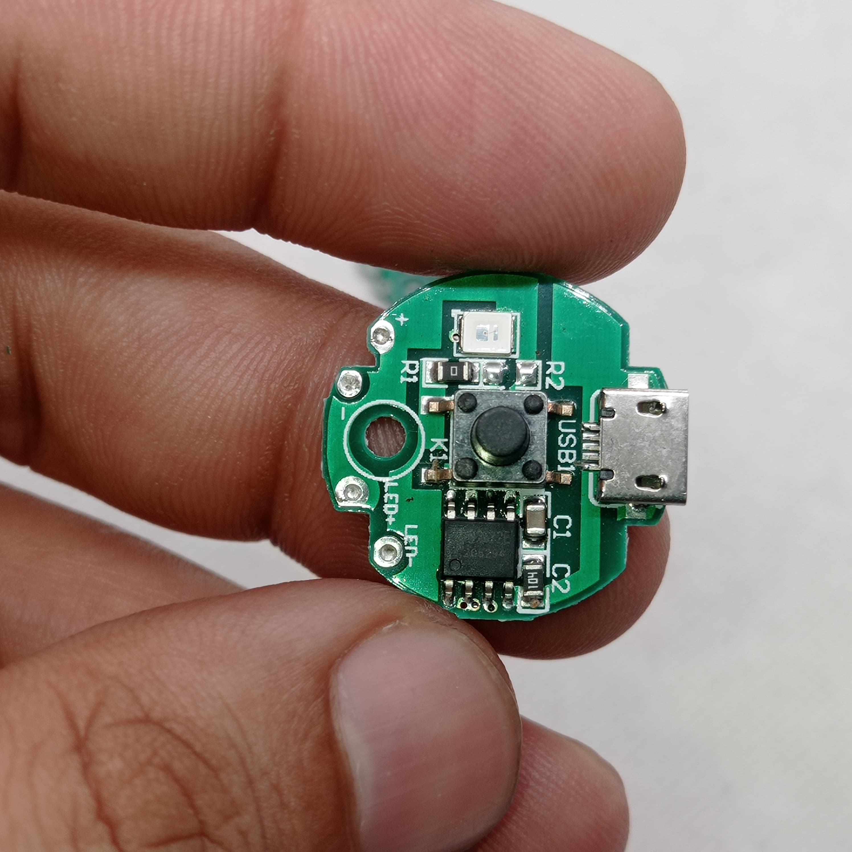 QW2672 Torch Light Emergency Light Controller Module - a circular green PCB with a micro-USB port, a push button, an LED, and solder pads for LED output.