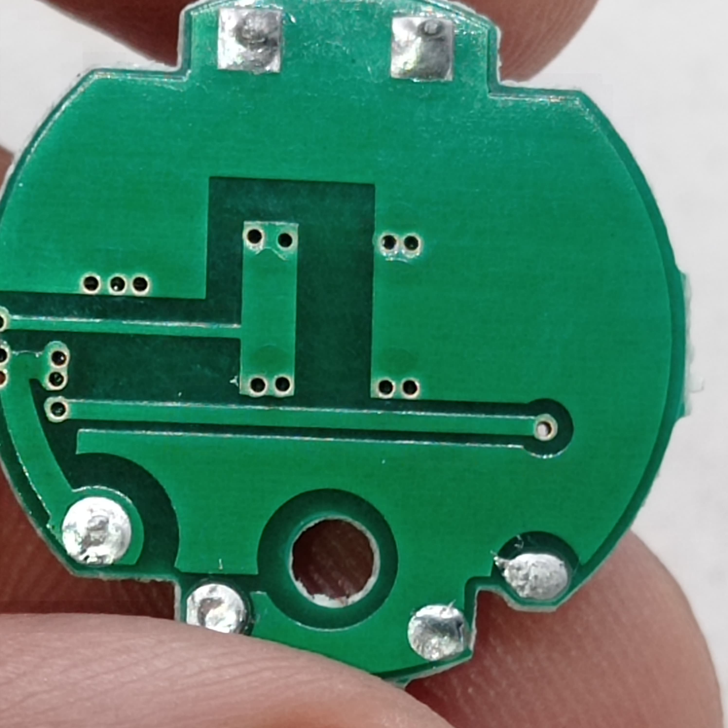 QW2672 Torch Light Emergency Light Controller Module - a close-up of the circular green printed circuit board showing solder points and copper traces.