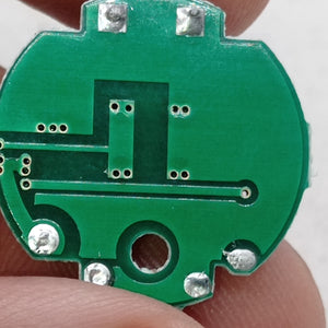 QW2672 Torch Light Emergency Light Controller Module - a close-up of the circular green printed circuit board showing solder points and copper traces.