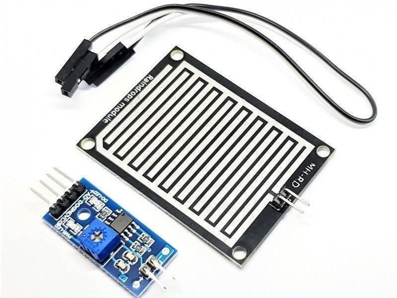 Rain Drops Detection Sensor Module In Paksitan - a black rectangular sensing board connected by wires to a blue control board with a potentiometer.