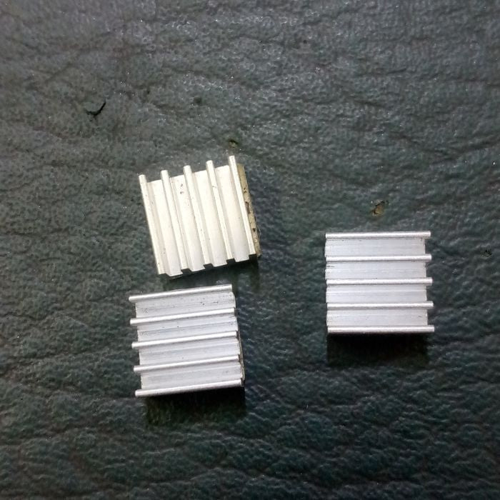 Raspberry Pi 3 Heatsink Cooler Pure Aluminum - three small, square, silver-colored aluminum heatsinks with vertical fins arranged on a dark surface.