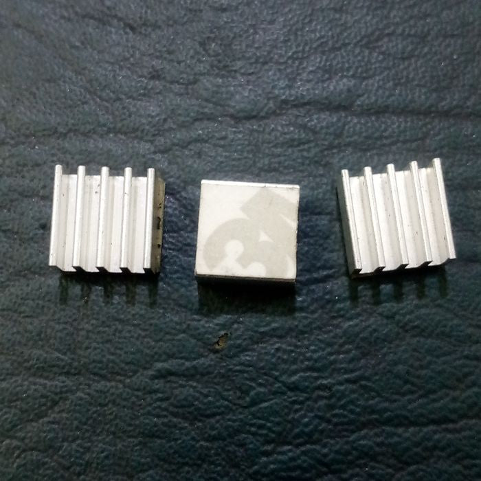 Raspberry Pi 3 Heatsink Cooler Pure Aluminum - three small square silver aluminum heatsinks, one with an adhesive backing visible.