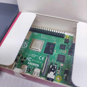 Raspberry Pi 4 2GB RAM Starter Kit - the green circuit board inside its white cardboard packaging with visible GPIO pins, HDMI ports, and camera connector.
