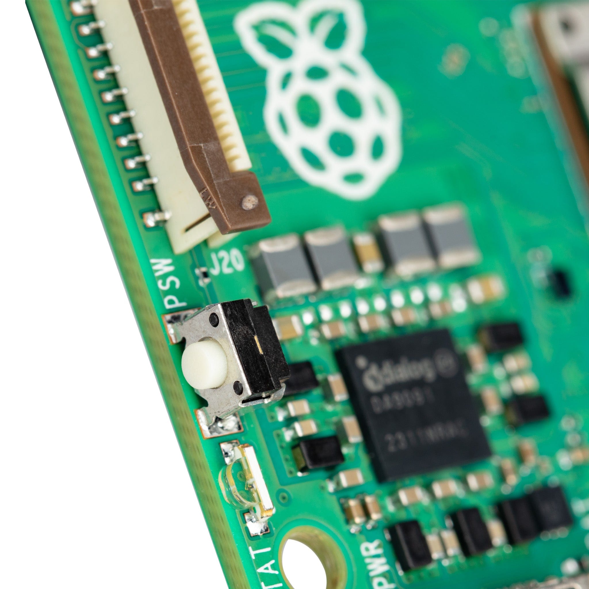 Raspberry Pi 5 4GB - a close-up of the green circuit board showing the white power button, a brown ribbon cable connector, and a Dialog chip.