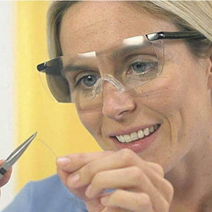 Rechargeable LED Magnifying Glasses - shown being worn by a person holding a small wire with tweezers, featuring clear lenses and a black frame.