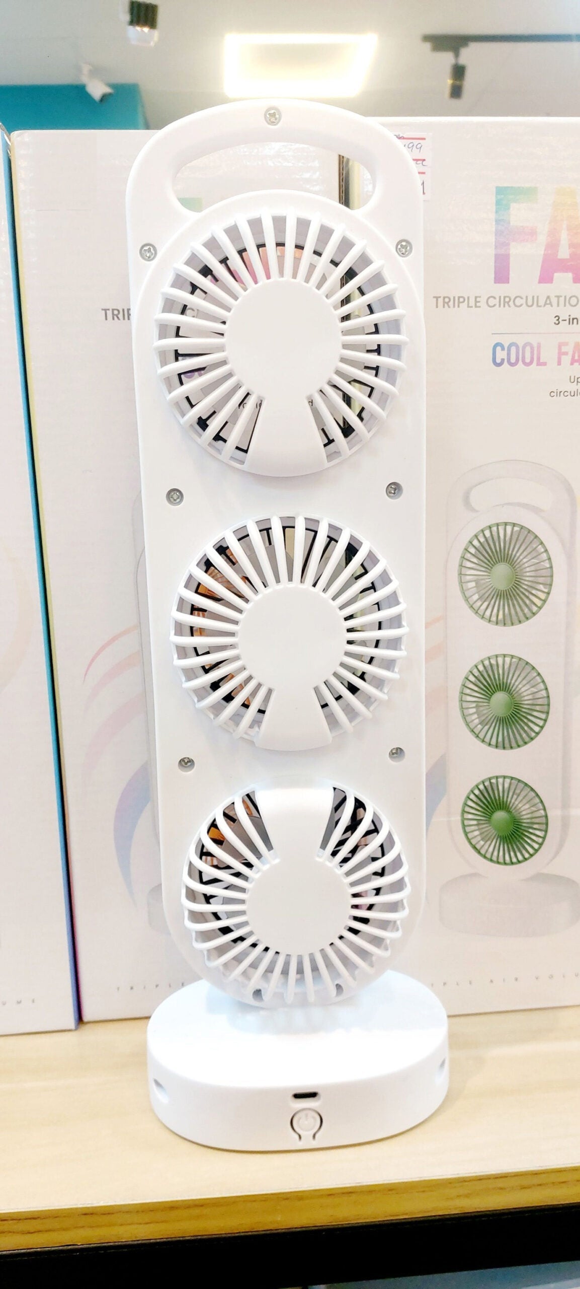 Rechargeable Triple Circulation Wind Fan price - a white vertical unit with three circular fans and a power button on the base, shown in front of its box.