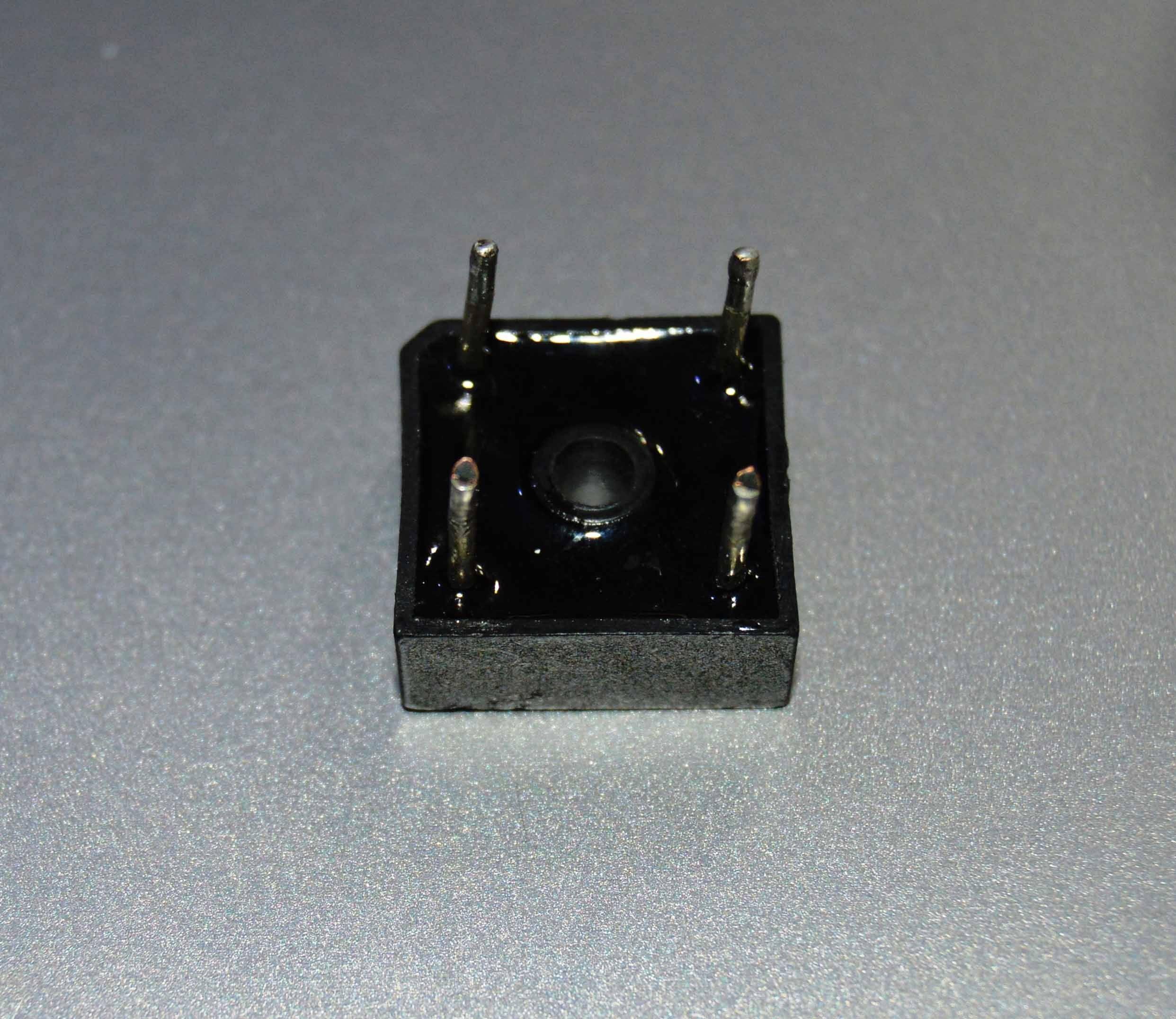 Rectron Bridge Ractifier BR104 (used Condition) - a black, square-shaped electronic component with four metal pins extending from its top surface.