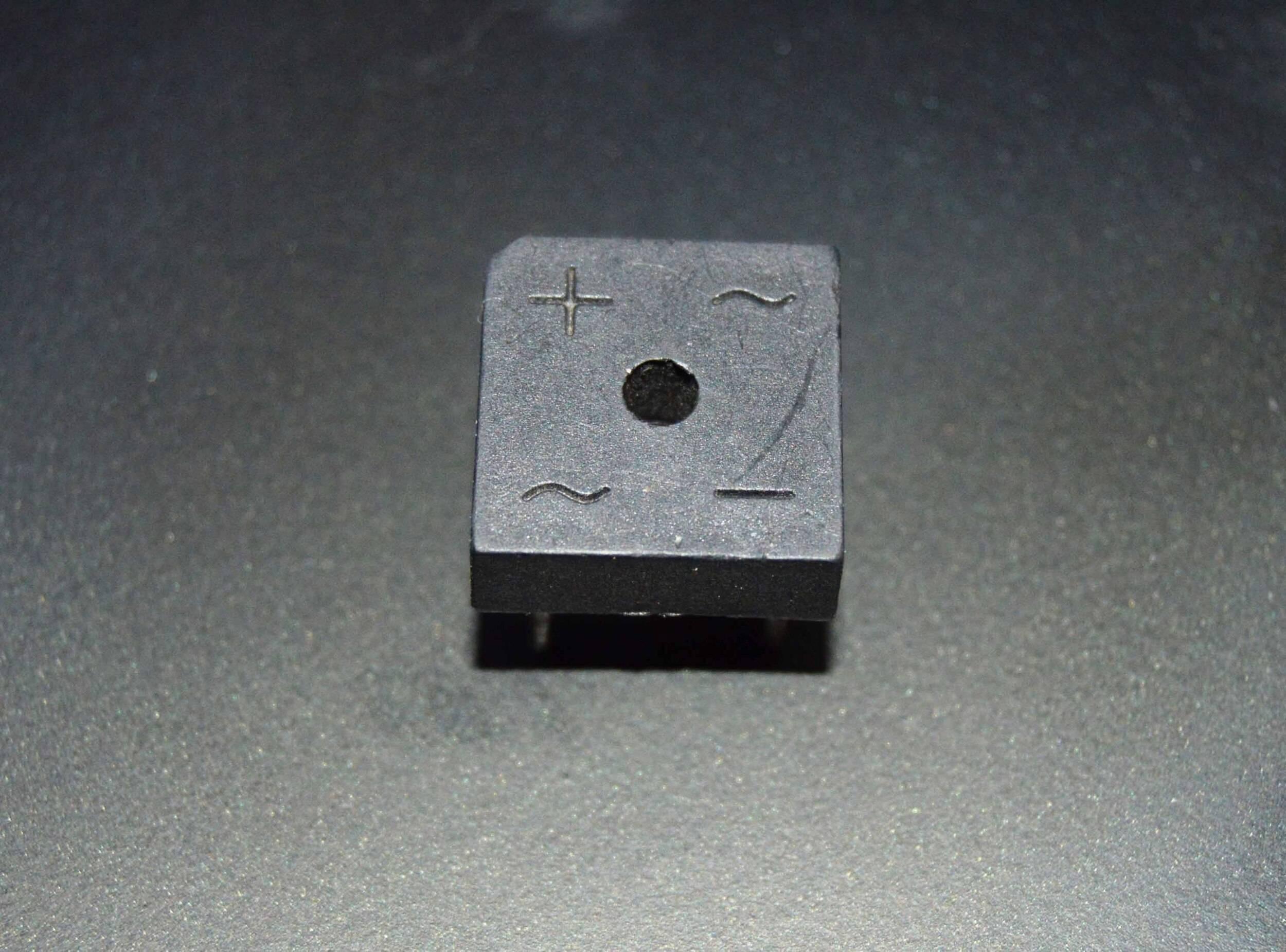 Rectron Bridge Ractifier BR104 (used Condition) - a black square-shaped electronic component with four pins and symbols for positive, negative, and AC inputs.