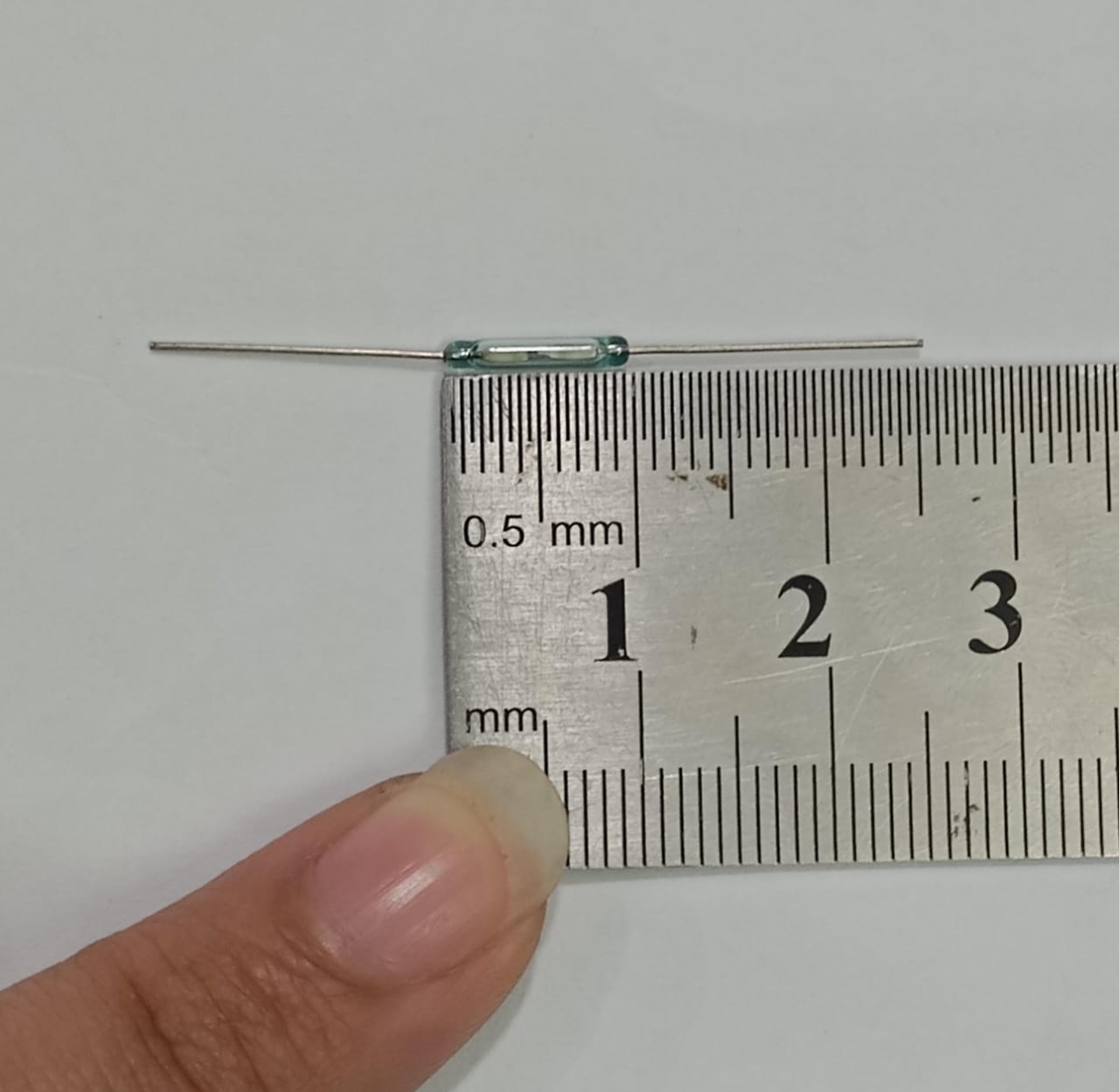 Reed Switch Sensor Reed Sensor Magneto Magnet Magnetic Switch Normally Close - a small clear glass component with two metal leads, shown being measured against a metal ruler in millimeters.