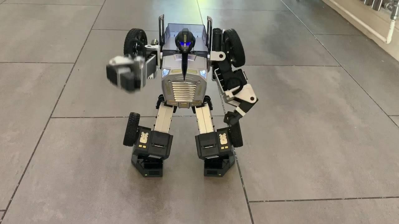 Robosen T9 - Advanced Programmable And Convertible Robot - STEM: Fun, Educational With Voice And App Control - standing in a humanoid form on a tiled floor with its right arm extended.