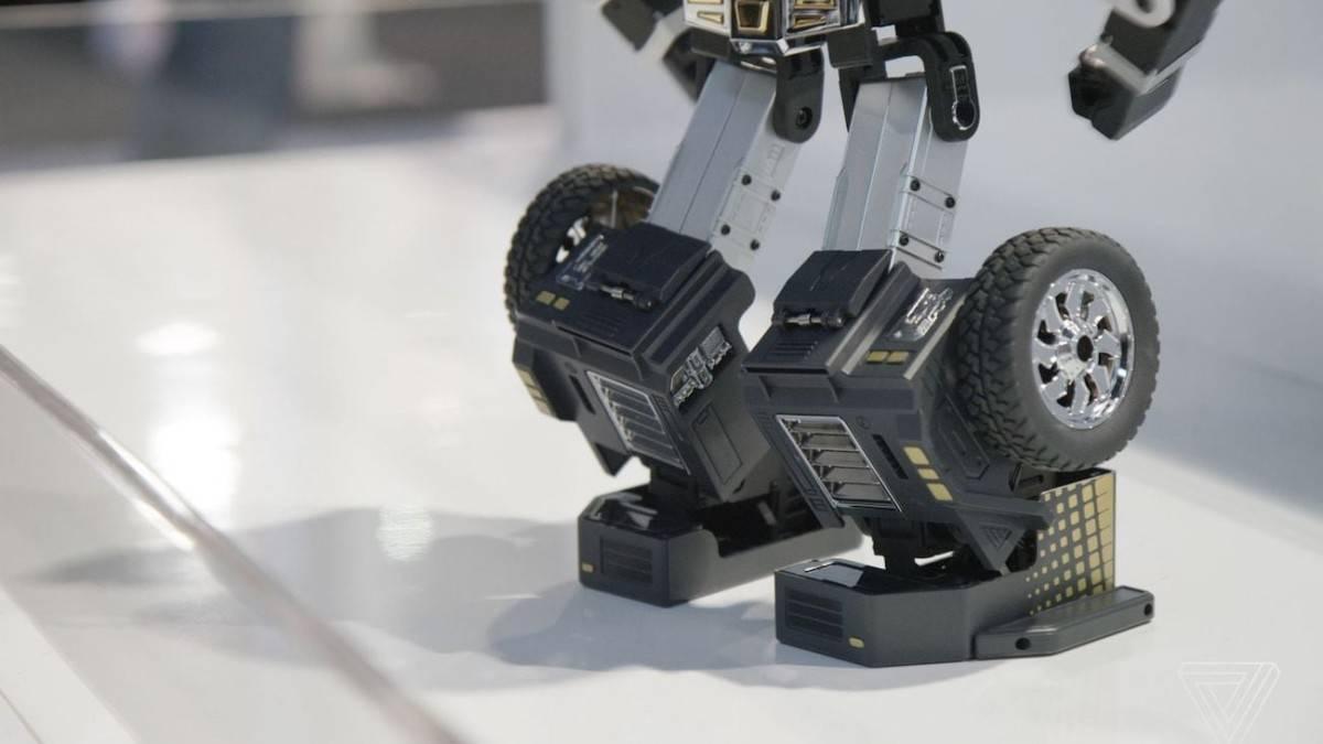Robosen T9 - Advanced Programmable And Convertible Robot - STEM: Fun, Educational With Voice And App Control - a close-up of the black and silver robotic legs featuring visible wheels, mechanical joints, and textured foot panels on a white surface.