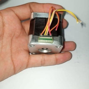 Round Shaft NEMA17 Stepper Motor For 3d Printer & CNC - a close-up view of the motor held in a hand, showing its black square body, silver face, and a 6-pin connector with wires.