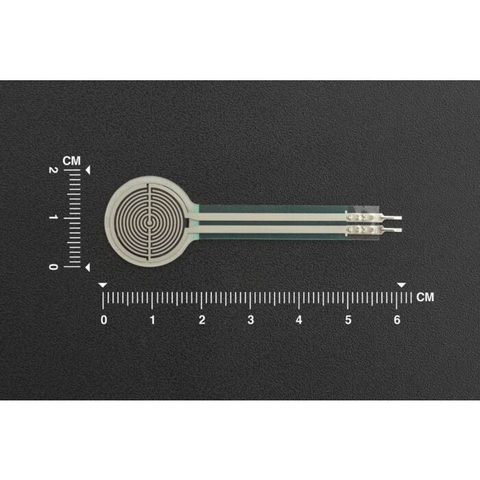 RP-C18.3-LT Thin Film Pressure Sensor - a circular white sensor with a flat ribbon tail and two metal connectors, shown against a centimeter ruler scale.