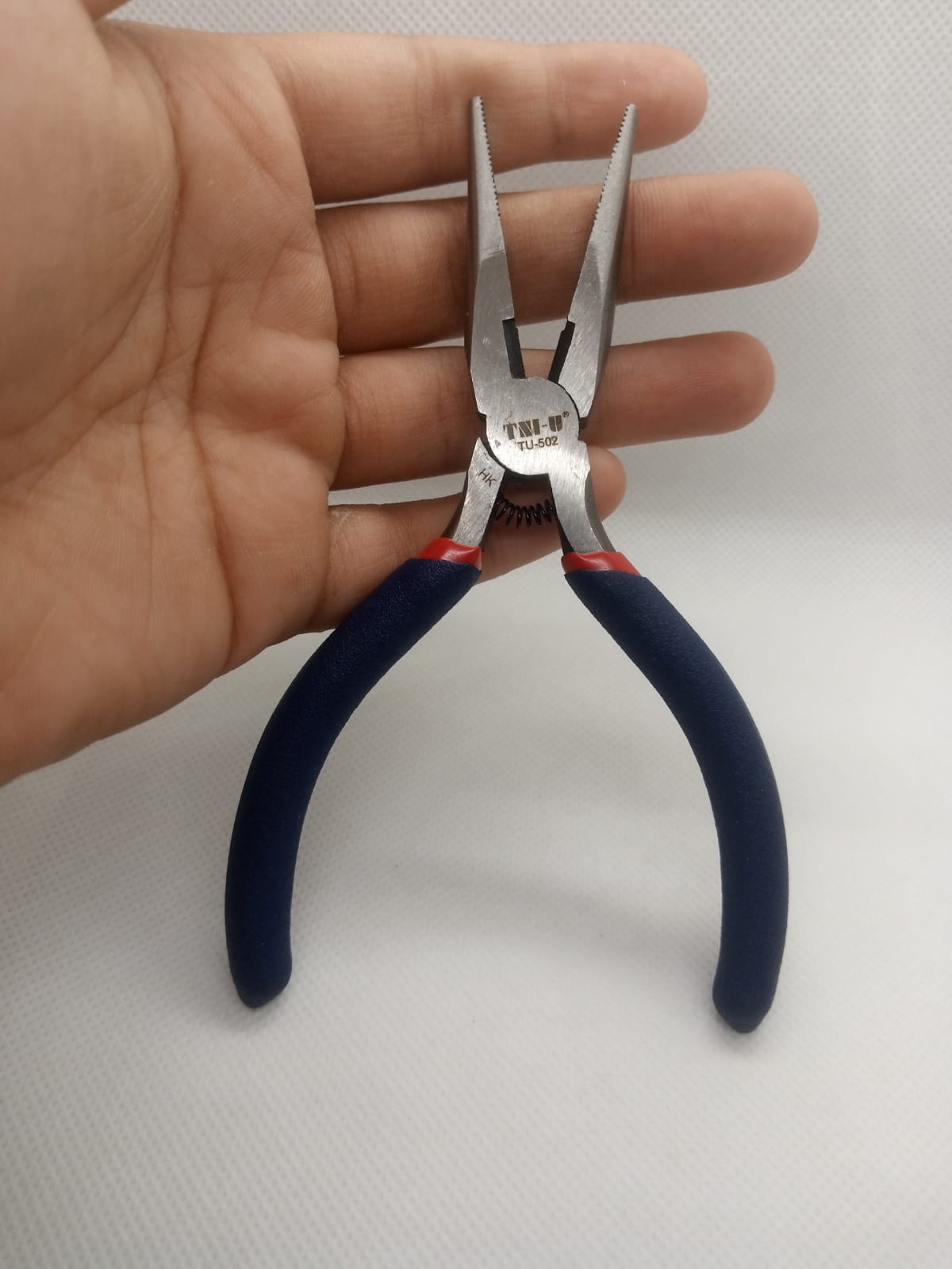 Santus St502 Needle Nose Plier Needle Nose Plier - with blue rubberized handles and a spring-loaded hinge being held in a hand against a white background.
