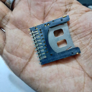SD memory card slot card - a close-up of a black plastic and metal connector component with multiple gold-plated pins held in a person's palm.