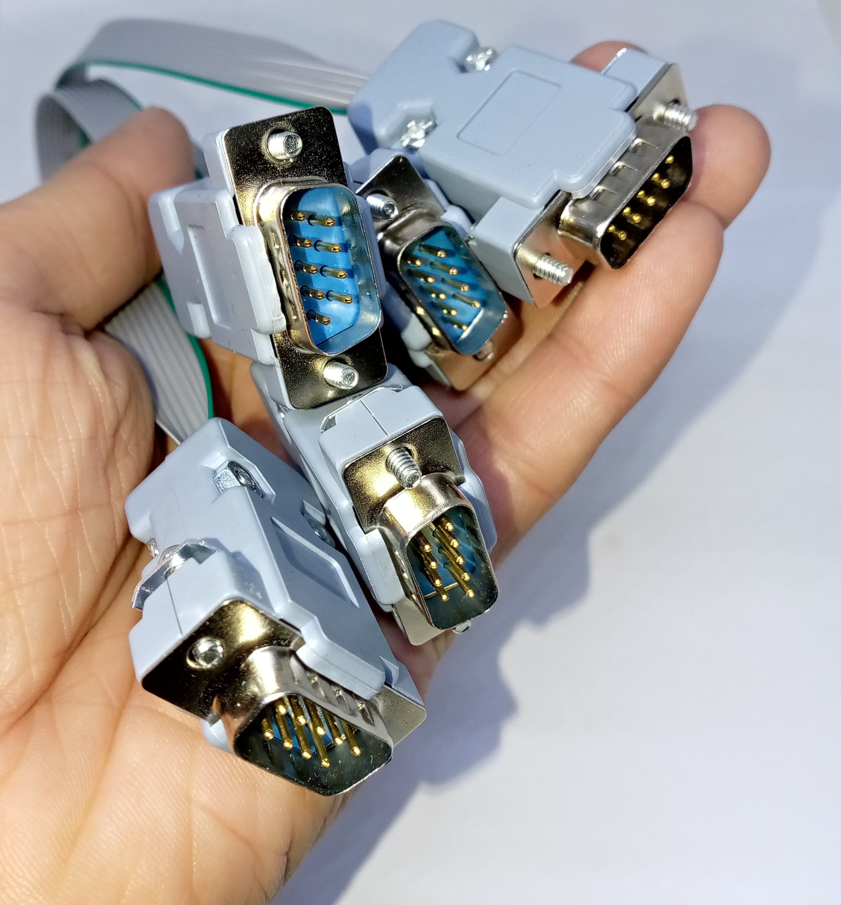Serial Modbus Daisy Chain Cable - shown as a hand holding multiple grey ribbon cables with 9-pin male DB9 serial connectors.