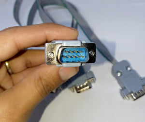 Serial Modbus Daisy Chain Cable - a close-up showing a grey ribbon cable with a male 9-pin D-sub connector held in a hand.