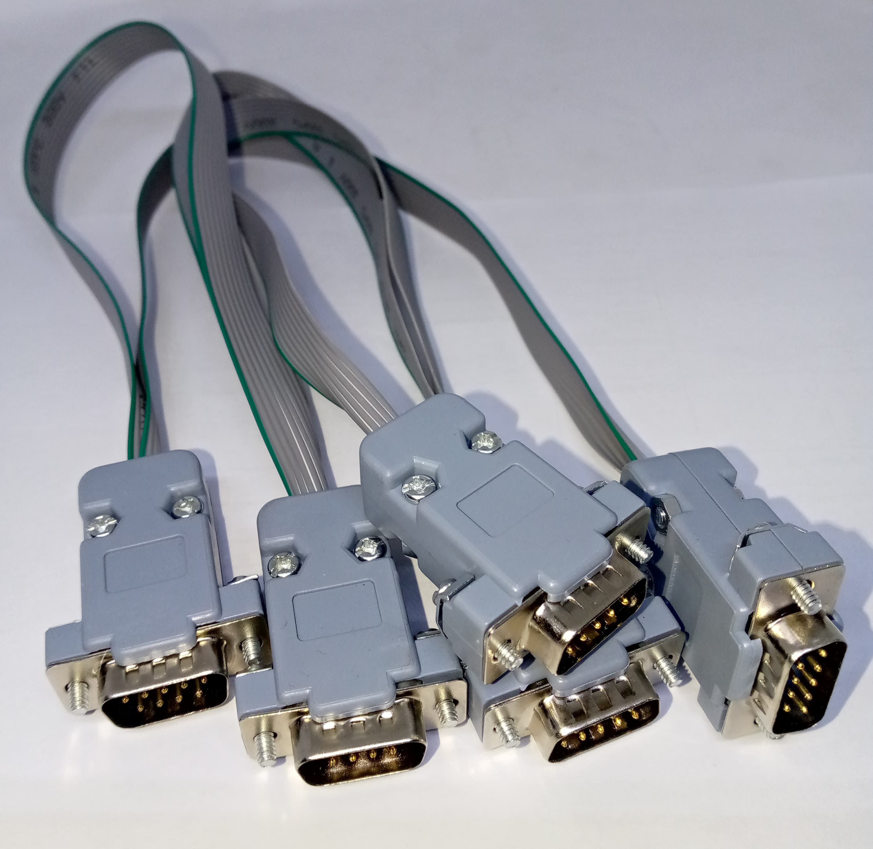 Serial Modbus Daisy Chain Cable - four grey DB9 male connectors linked together by flat ribbon cables against a white background.